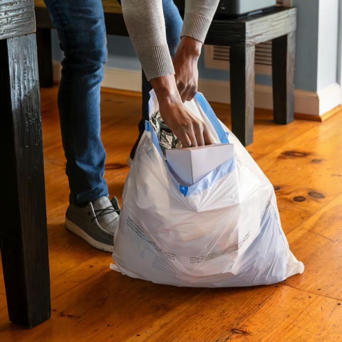 person putting trash into a Hefty medium sized trash bag