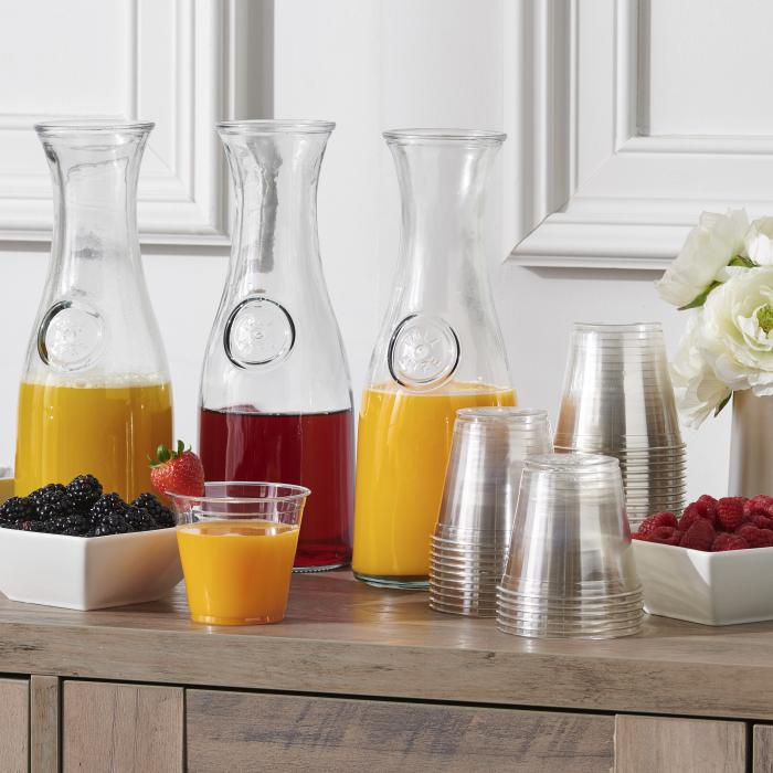 Juice bar with multiple juices in carafes and clear plastic cups alongside