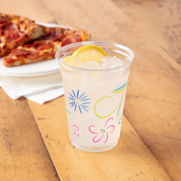 Hefty Party Perfect Flower Printed Cup filled with lemonade and sitting alongside a slice of pizza