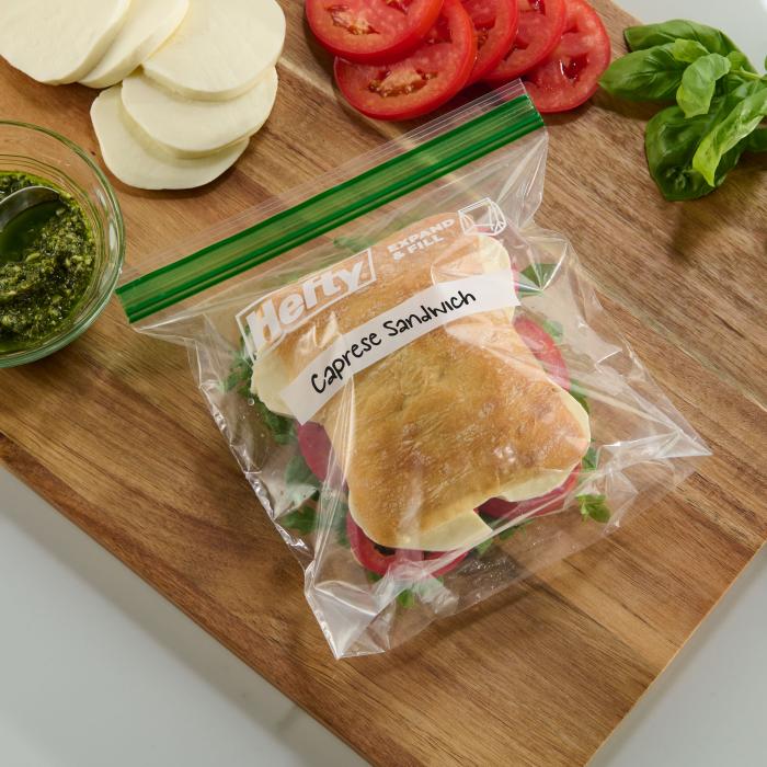 Caprese sandwich in a Hefty XL Sandwich bag sitting on a wood cutting board